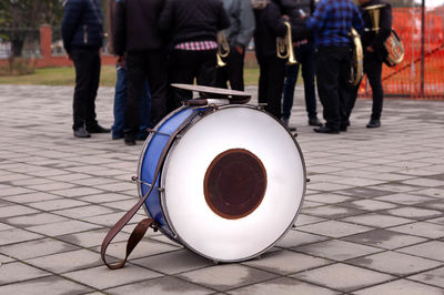 View of drum on footpath with people in background at city