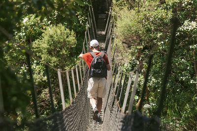 Rear view of man walking on footbridge