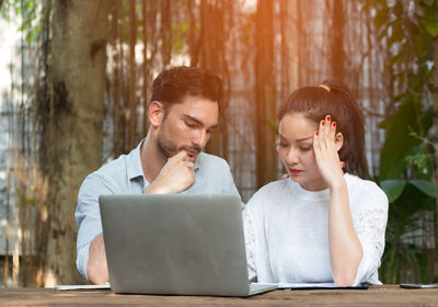 Young man using phone while sitting outdoors