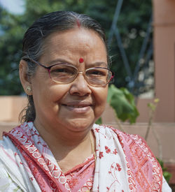 Portrait of a simple looking aged bengali woman smiling in sunlight.