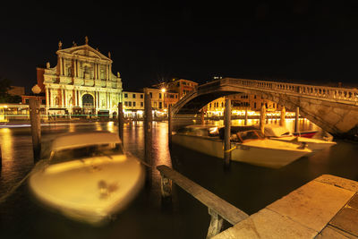 Arch bridge over canal in city at night