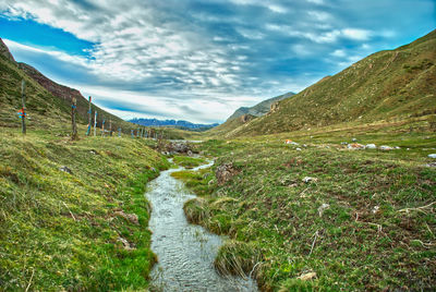 Scenic view of stream amidst land against sky