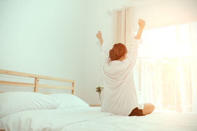 Rear view of woman lying on bed at home