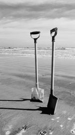 Close-up of deck chairs on beach against sky