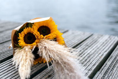 A bunch of sunflowers lies on a pier.