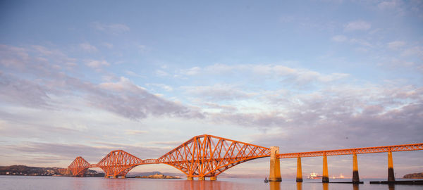 Low angle view of bridge over river against cloudy sky