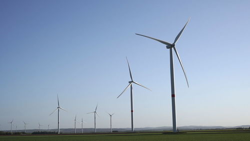 Wind turbines on field against clear sky
