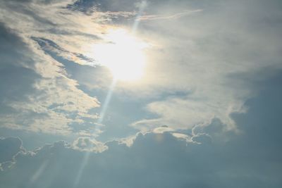 Low angle view of sunlight streaming through clouds