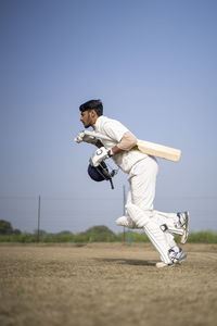 Side view of man exercising on field against clear sky