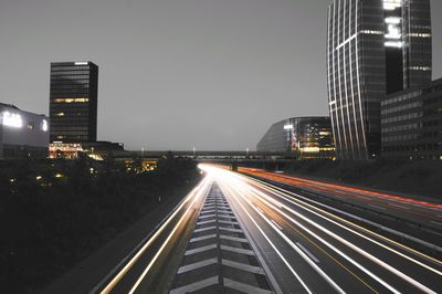 Light trails on road amidst buildings in city at night