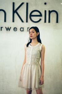 Portrait of young woman standing against wall