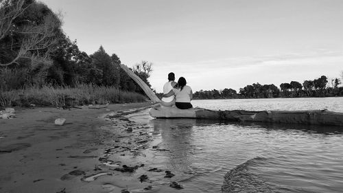 Couple sitting on dead tree by river