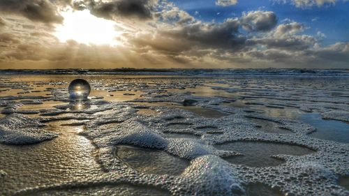 Surface level of sandy beach against sky during sunset