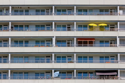 Facade of a big apartment building with yellow sunshades on one of the balconies