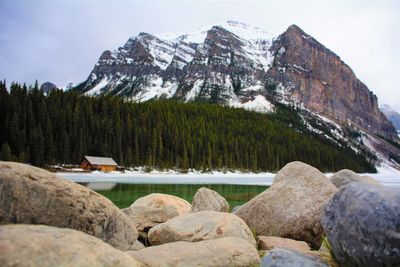 Rocks by lake against sky during winter