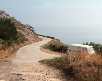 Footpath by road against sky