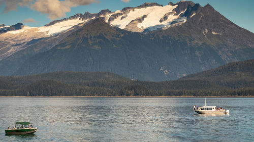 Sailboat on sea by mountain against sky