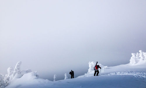 People skiing on snowcapped mountain against clear sky