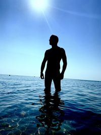 Silhouette man standing in sea against sky