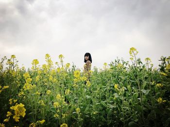 Woman standing on field against yellow flowers