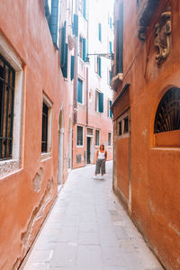 Man walking on footpath amidst buildings in city