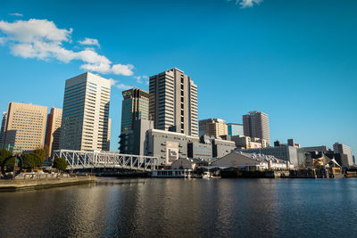 River by buildings against blue sky in city