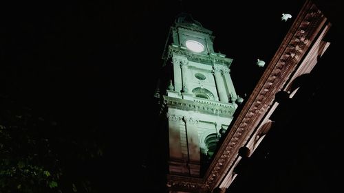 Low angle view of illuminated clock tower at night