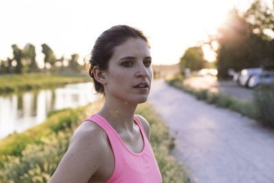 Confident sportswoman looking away while standing in park during sunset