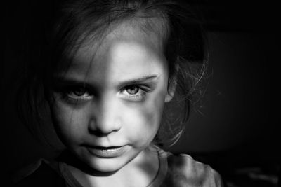 Close-up portrait of young woman over black background