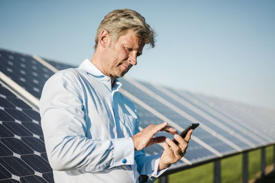 Businessman using smartphone at solar park