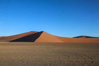 Scenic view of desert against clear blue sky