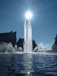 Fountain in swimming pool by sea against sky on sunny day