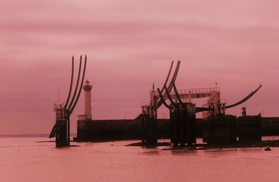 Silhouette cranes against sky at sunset