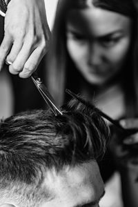 Close-up of woman cutting man hair at shop