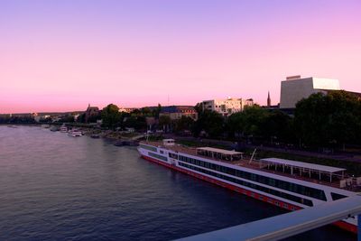 Scenic view of river by buildings against clear sky at sunset