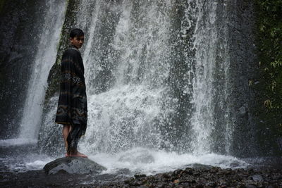 Wearing a lombok-indonesian songket cloth enjoying the freshness of a waterfall