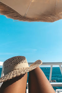 Midsection of woman with hat relaxing on yacht against sky