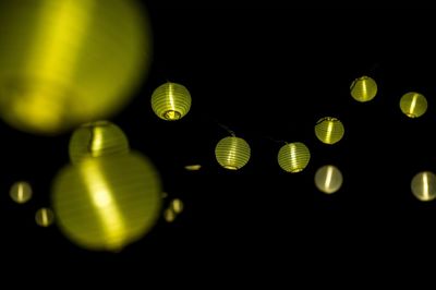 Low angle view of illuminated lights against black background