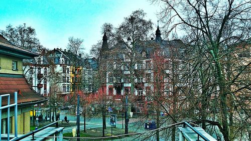 Low angle view of bare trees against buildings