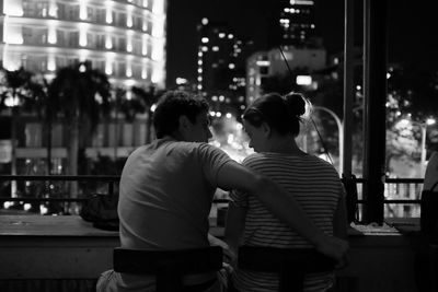 Rear view of couple kissing in city at night