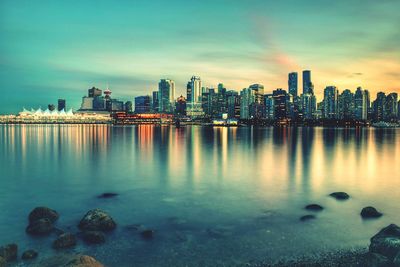 View of city at waterfront against cloudy sky