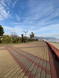 Surface level of footpath by street against sky