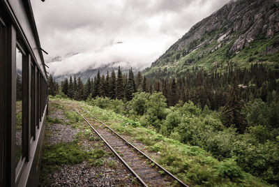 Scenic view of train and mountain against cloudy sky