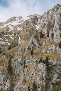 Low angle view of rock formation against sky with little snow