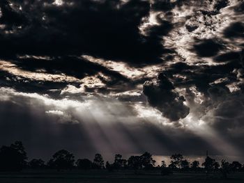 Low angle view of sunlight streaming through clouds