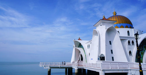 Traditional building by sea against sky