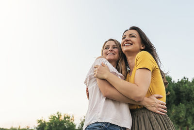 Side view of smiling young woman against sky