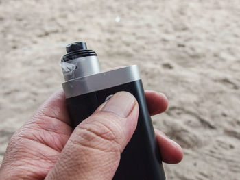 Cropped hand holding electronic cigarette at beach