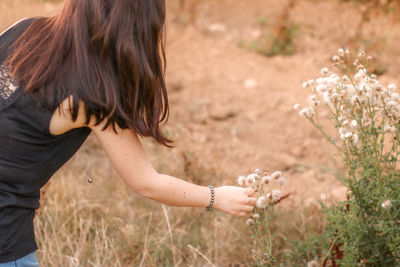 Midsection of woman with arms raised on field