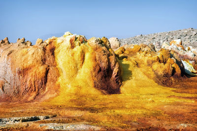 Rock formations on landscape against clear blue sky